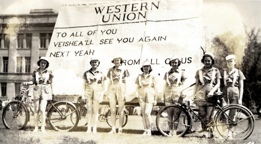 1939 parade entry - 7 girls next to bicycles in front of a large telegram that says " Western Union - To all of you VEISHEA'll see you again next year -- From all of us" 