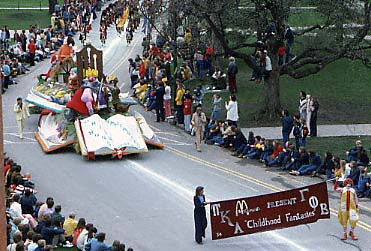 VEISHEA parade with Ronald McDonald holding a banner in front of a parade float.